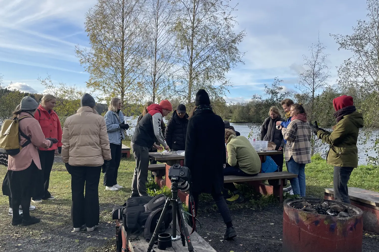 Students working at outdoor tables by a lake