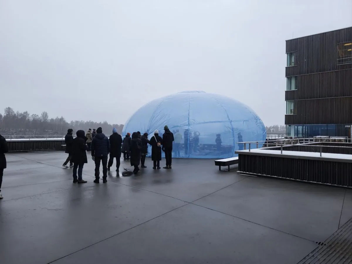 People gathered beside the blue dome on the snowy Arts Campus terrace