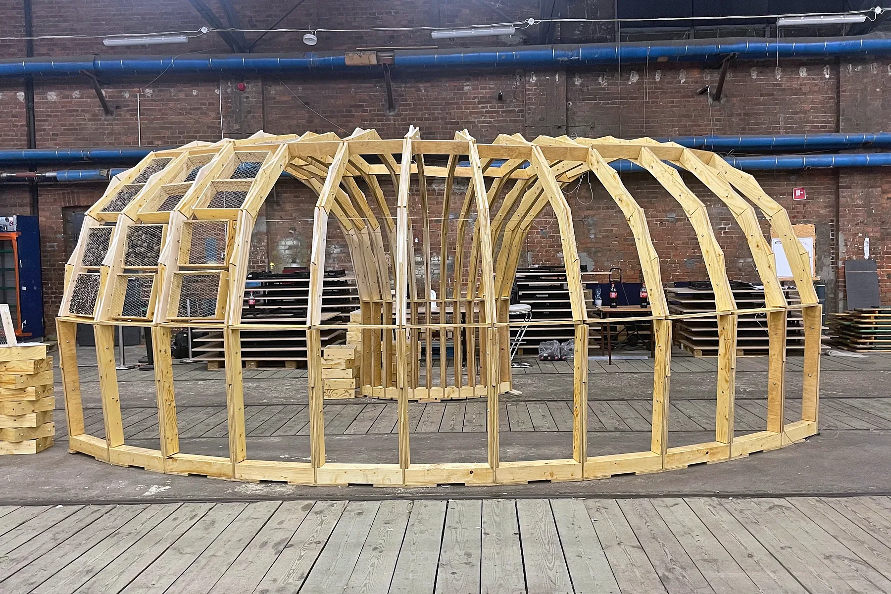 The armadillo from the side: a long vault of timber arches in a large hall, some of its bays filled with nesting boxes, boxes stacked beside it