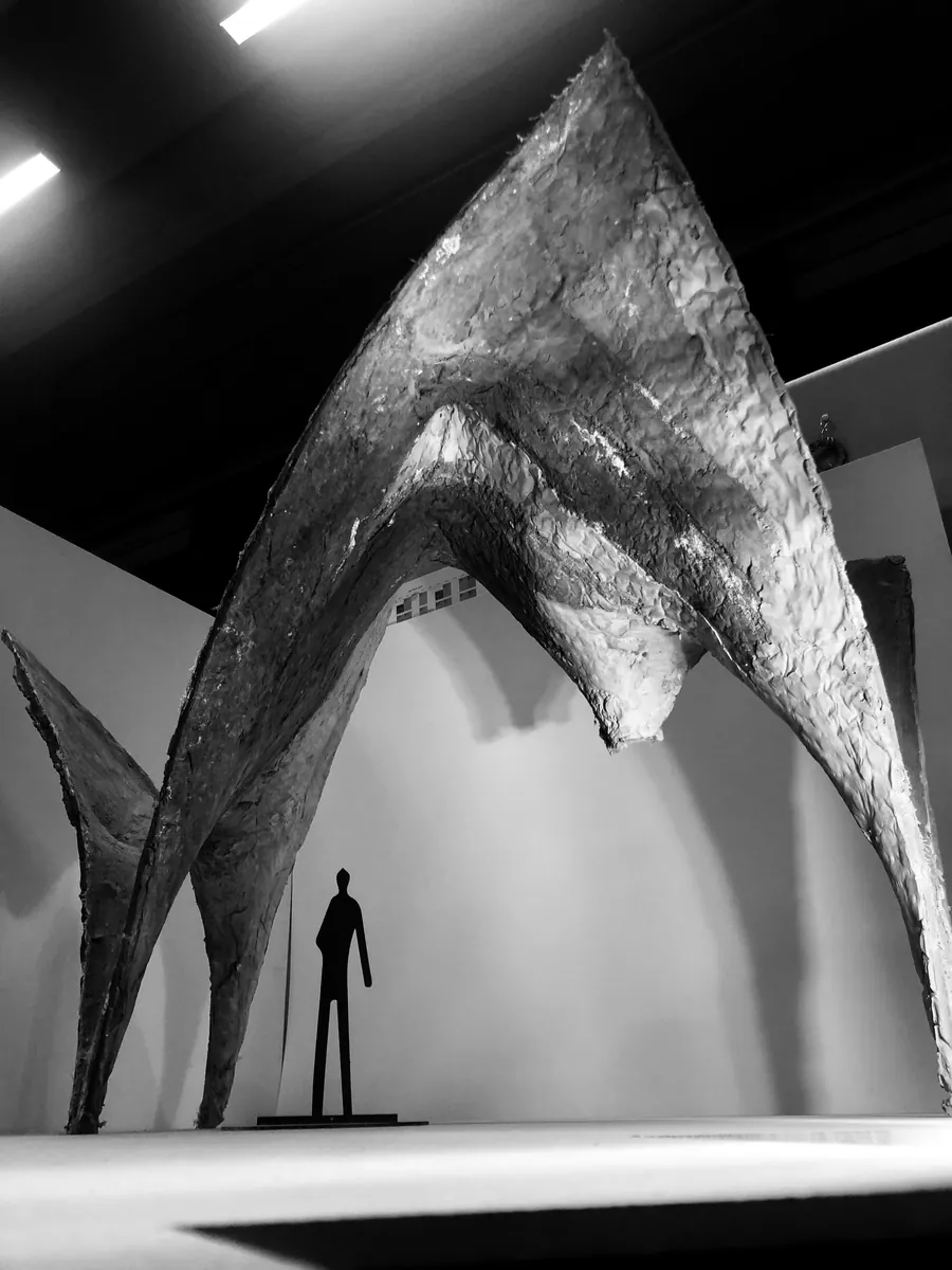 Black and white photograph of a tall shell model with a small human figure for scale