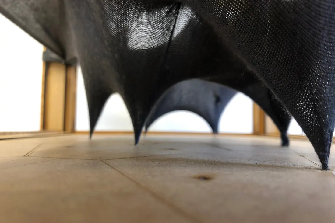A dark coated fabric model with four pointed supports
