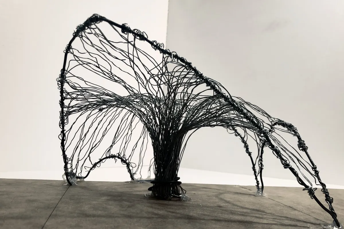 A model of black wire and net, its surface hanging between thin columns